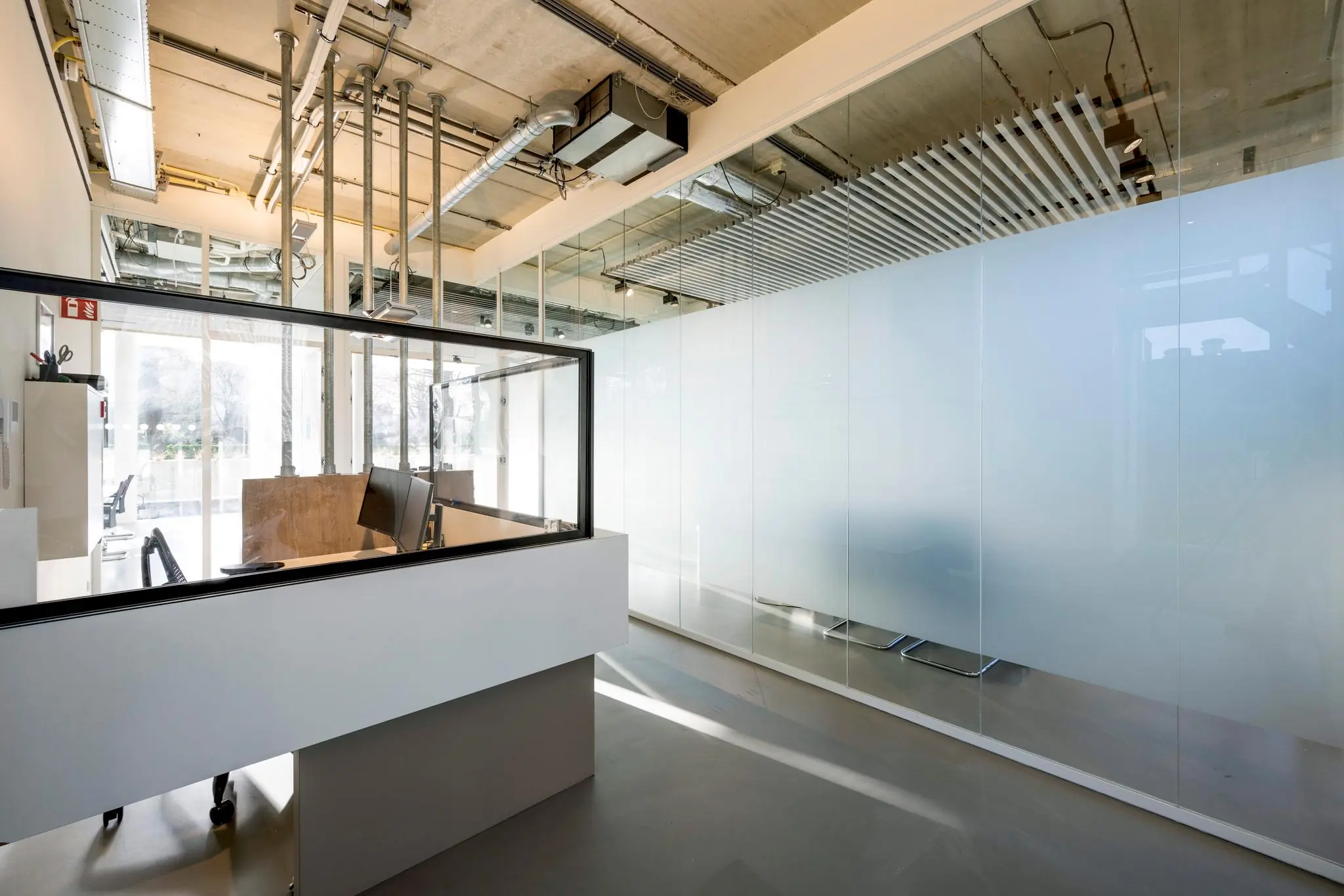 Moderne ontvangstbalie met glazen afscheiding in een strak ingericht kantoorpand aan de Fred. Roeskestraat.